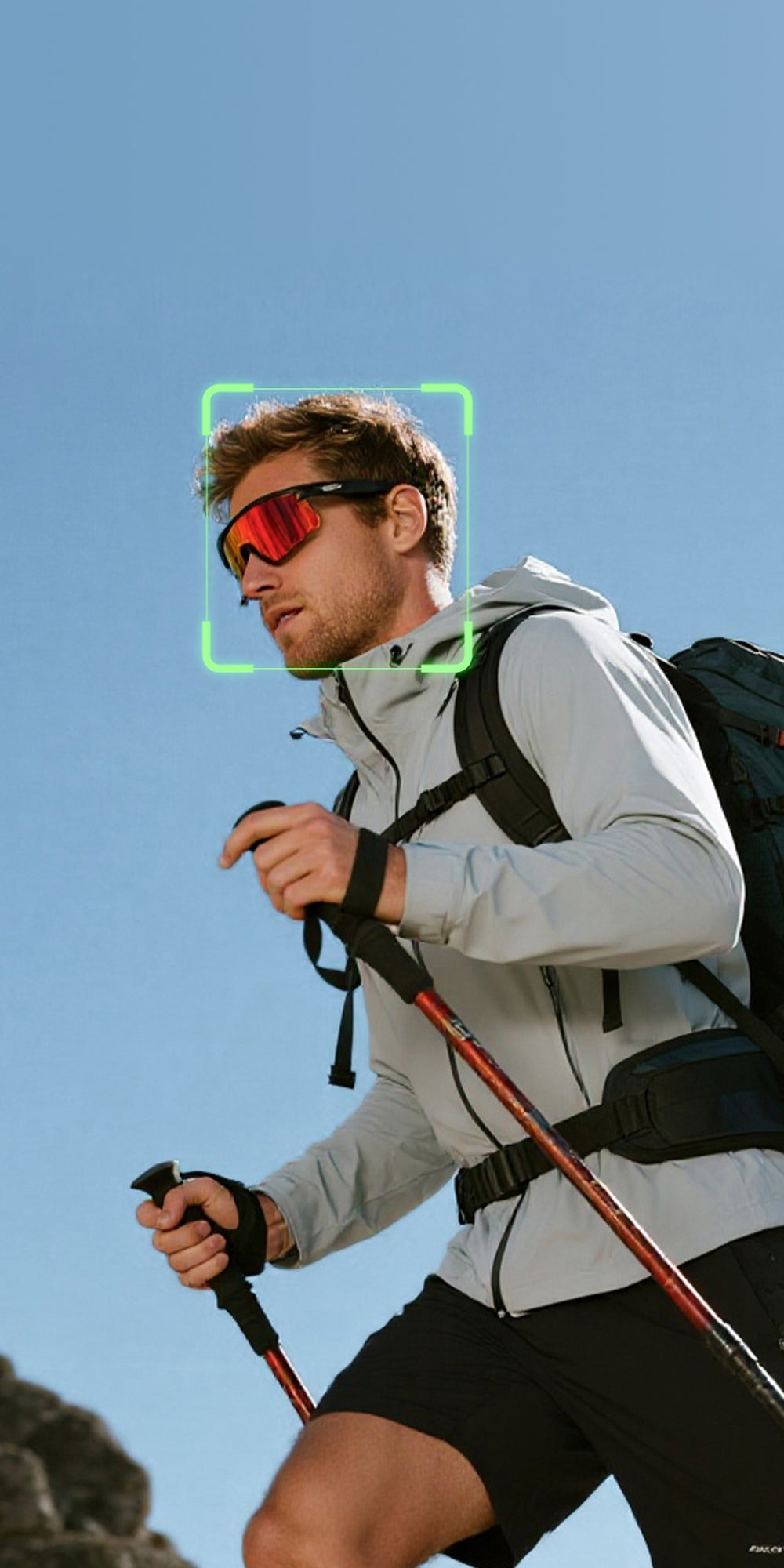 Man hiking with sunglasses and a backpack against a clear blue sky