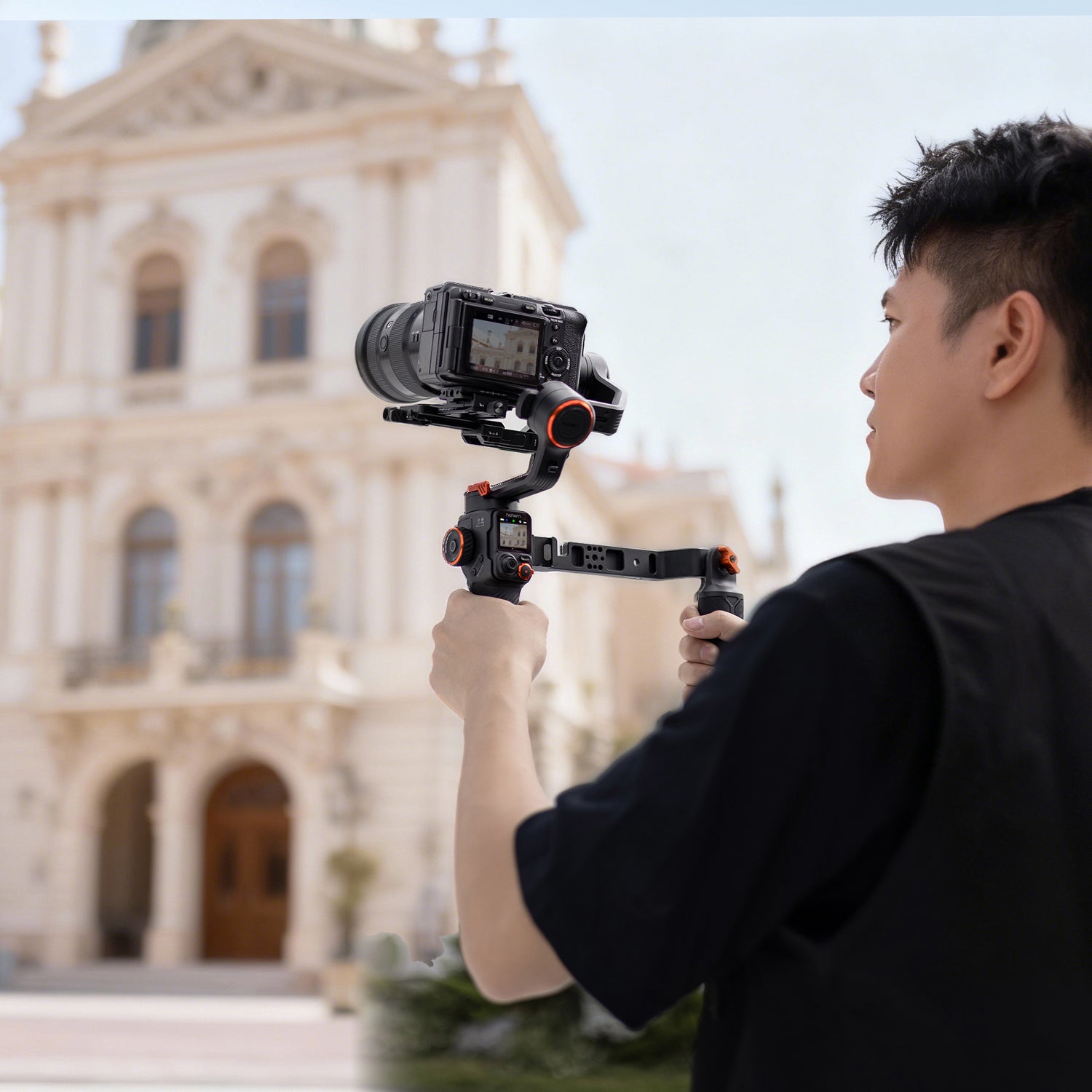 Person using a MT3 pro camera on a gimbal in front of a large building