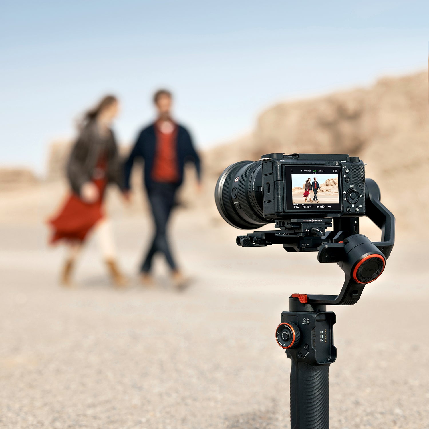 Camera on a tripod recording two people walking in the desert