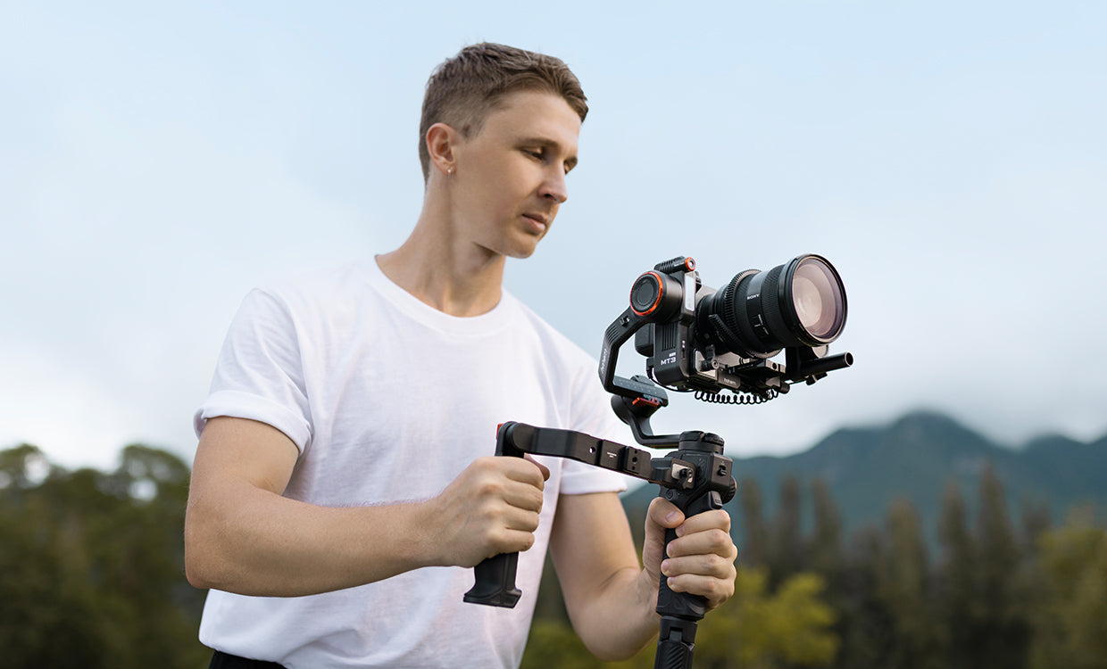Man holding a camera stabilizer with a scenic background